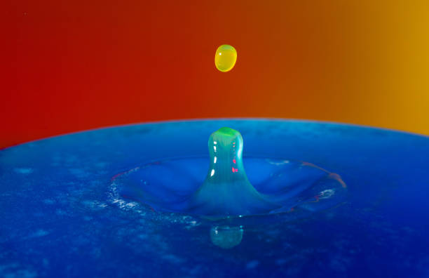 istock Droplet photography: a yellow drop falling into the blue water 1150590406