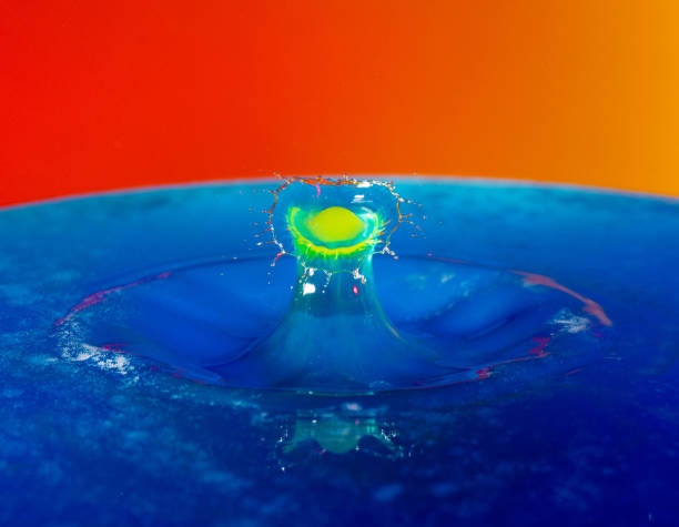 istock Droplet photography: a yellow drop falling into the blue water 1150590417