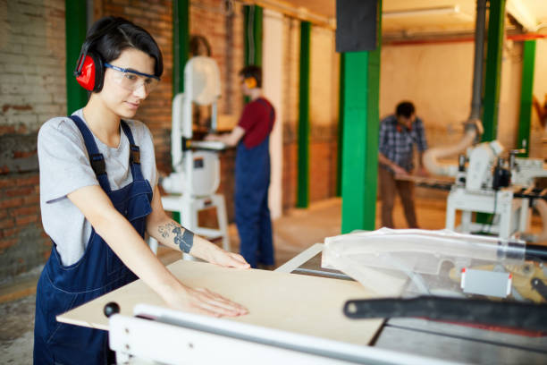 Concentrated lady cutting wooden plank