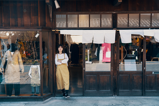 Female small business owner standing in front of her clothing store in Japan