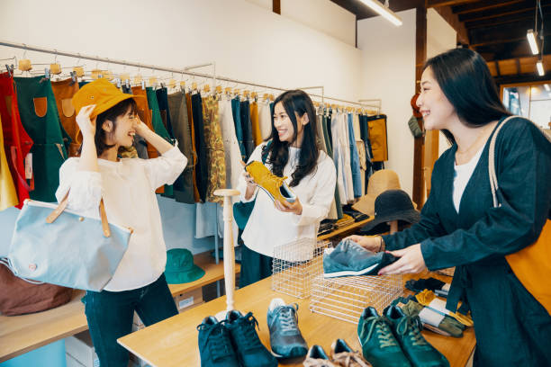 tre donne che fanno shopping insieme in un negozio di abbigliamento - boutique shopping women clothing foto e immagini stock