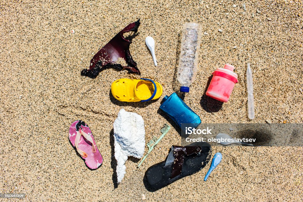 Various types of plastic waste collected on the beach on sand background Various types of plastic waste collected on the beach. Single-use spoons, rubber shoes, different bottles, styrofoam. Environmental pollution problem Bag Stock Photo