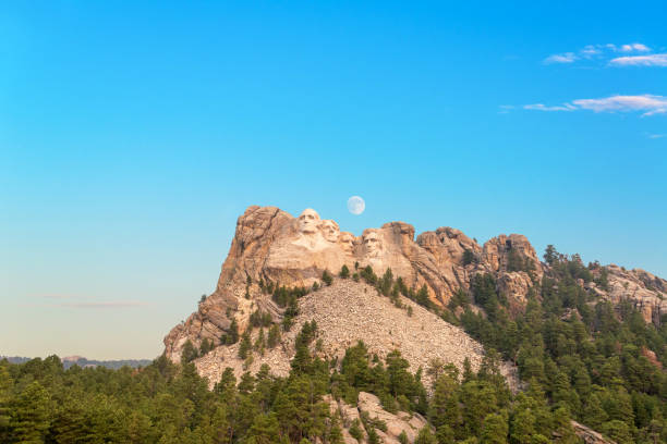 Mount Rushmore and Moon Mount Rushmore with the moon visible near Keystone, South Dakota keystone south dakota photos stock pictures, royalty-free photos & images