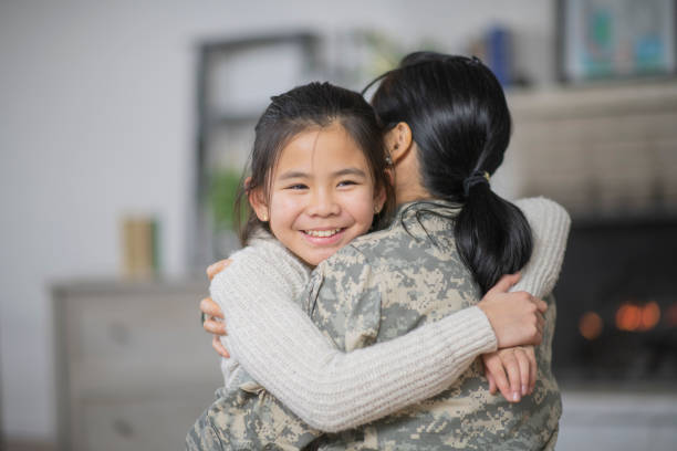Happy Together A mother and daughter are hugging in their living room. The mother is wearing a military uniform. They are both excited that she is back from her deployment. filipino family reunion stock pictures, royalty-free photos & images
