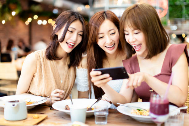istock Happy friends having dinner and watching smart phone in  restaurant 1150613435