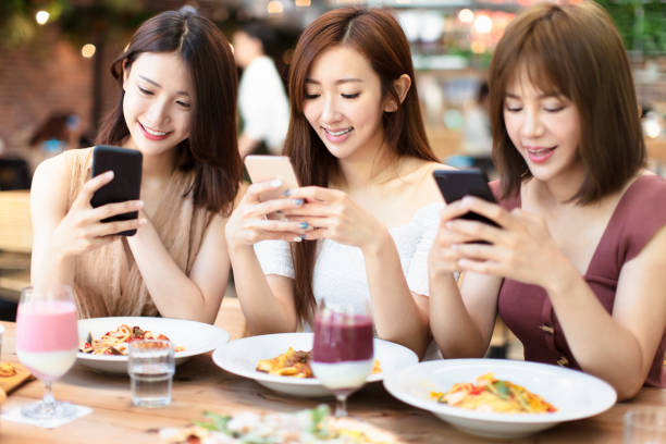 istock Happy friends having dinner and watching smart phone in  restaurant 1150613442