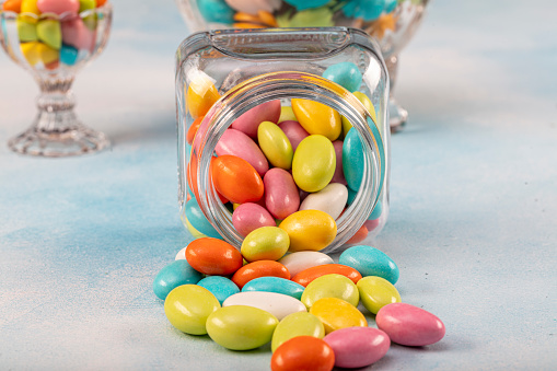 Sweet sugar candies in glass jars on brown vintage wooden background