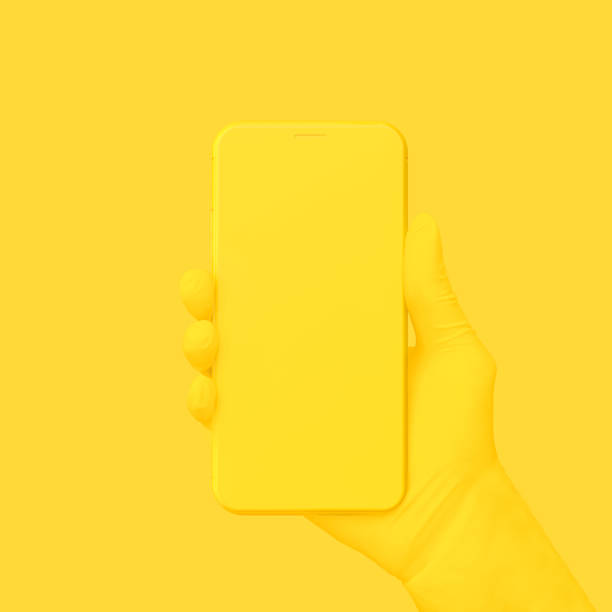 mano amarilla sosteniendo el teléfono sobre fondo amarillo. - amarillo color fotografías e imágenes de stock