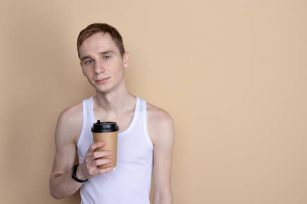 istock Skinny handsome guy drink from coffee or tea cup. Morning refreshment and drink 1150634825