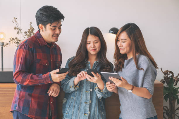 istock Three young asian people using and looking at mobile phone and tablet pc together 1150637384
