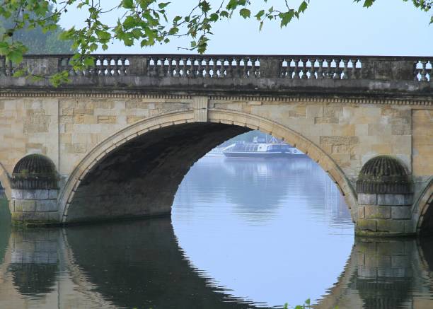 A cool still spring morning on the River Thames at Henley with the ancient five arch stone bridge in the foreground.