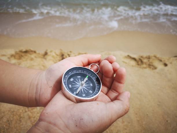 istock A young boy holding on a compass pointed to the north facing to the ocean. 1150641447