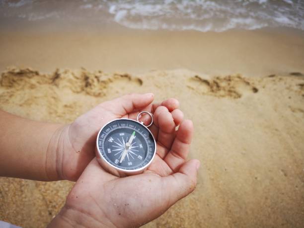 istock A young boy holding on a compass pointed to the north facing to the ocean. 1150641448