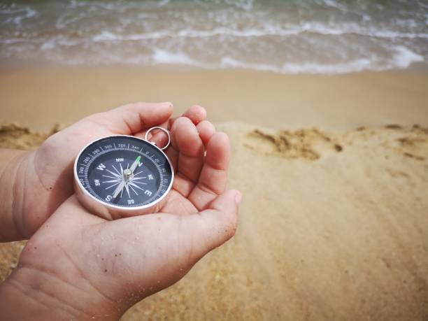 istock A young boy holding on a compass pointed to the north facing to the ocean. 1150641449
