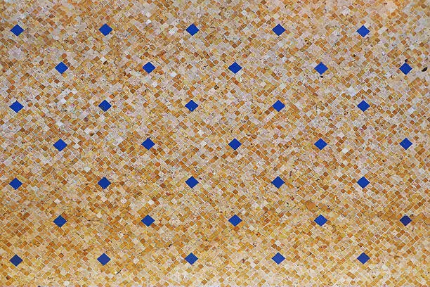 vintage floor tile texture in yellow and decorated with little dark blue square tile