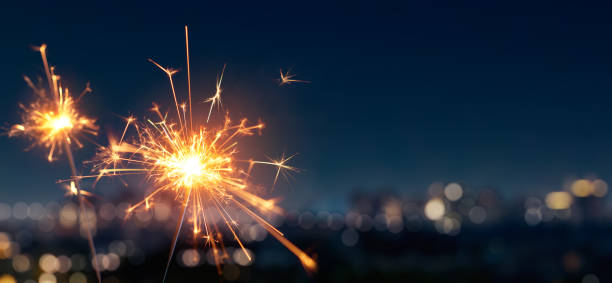 Burning sparkler with blurred bokeh cities light background stock photo