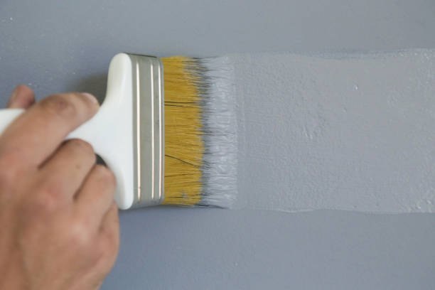 istock Man painting with a paintbrush over a grey wall 1150649013