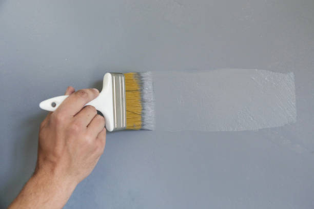 istock Man painting with a paintbrush over a grey wall 1150649028