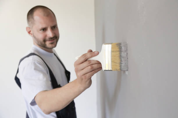 istock Man painting with a paintbrush over a grey wall 1150649211
