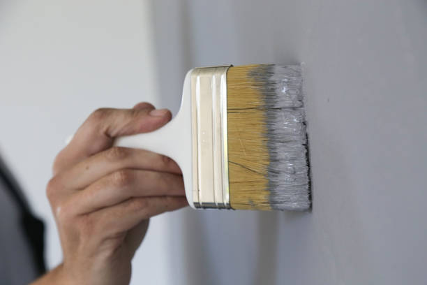 istock Man painting with a paintbrush over a grey wall 1150649330