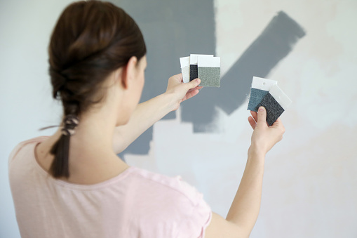 Young women choosing a perfect shade of grey for walls in her new home