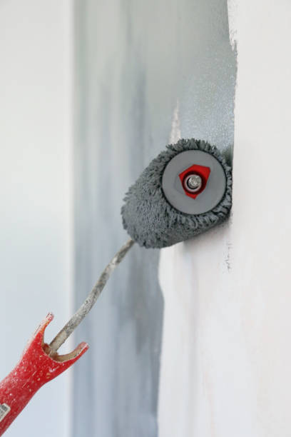 istock Paint roller. Painting with gray paint over a white wall 1150649511