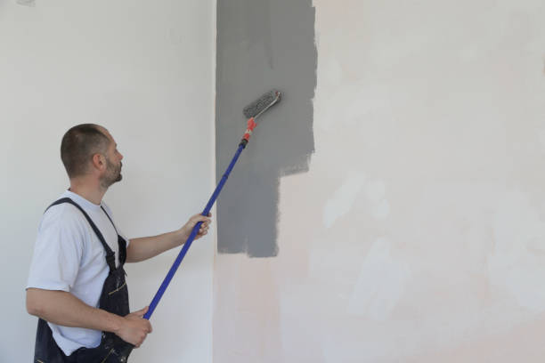 istock Man painting with gray paint over a white wall 1150649645