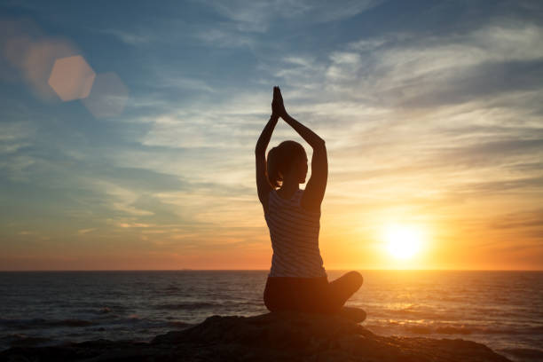 istock Silhouette young woman practicing yoga on the beach at sunset. 1150650680