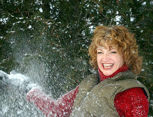 laughing woman playing in the snow stock photo