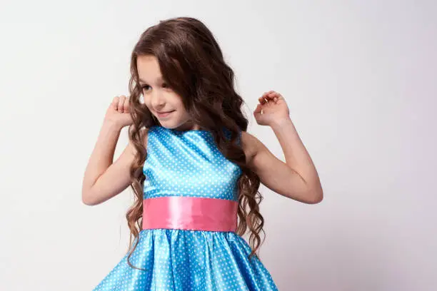 Beautiful little girl. Blue dress. White background.