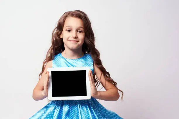 Beautiful little girl. Modern technologies. Lush blue dress.