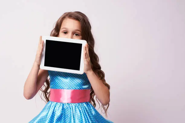 Little girl. Fluffy dress. Modern tablet.