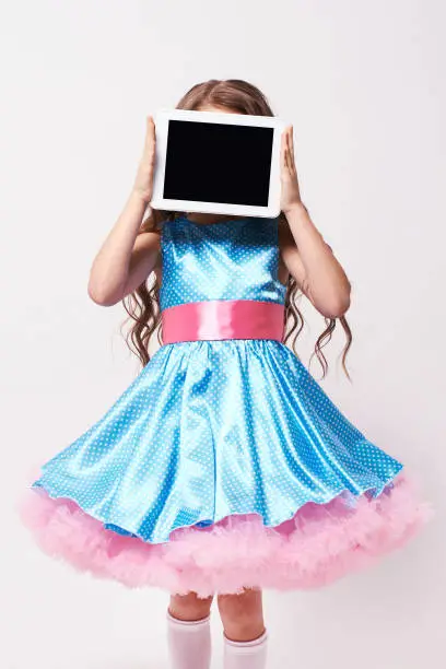 Little girl. Fluffy dress, Modern tablet.