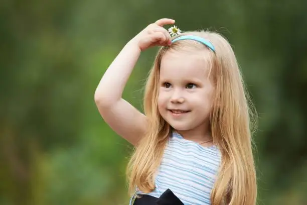 Little girl. Portrait child. Blonde. Chamomile. Green background