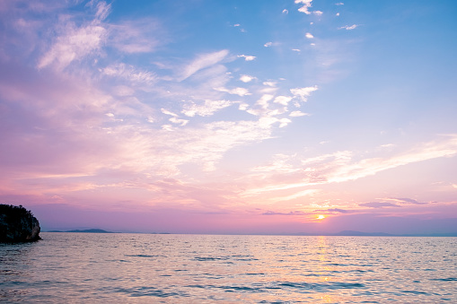 Sunset purple dusk sky with sun at orange ocean horizon and ship silhouette