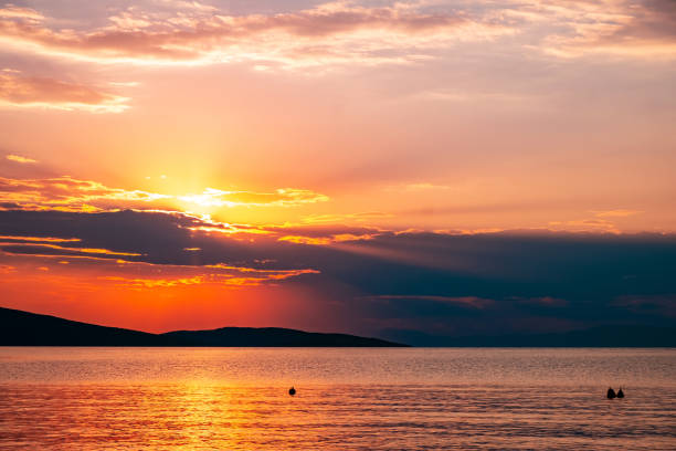 istock Sunbeams through clouds at sunset above the sea surface 1150653922