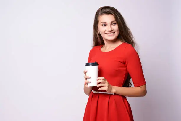 Girl holding coffee. Red dress. White glass.