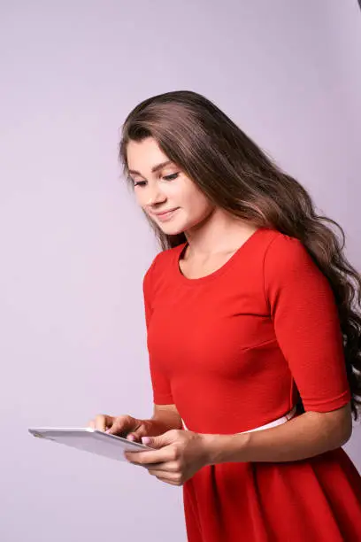 Modern tablet. Red dress. Young girl.