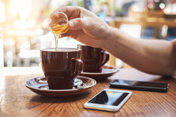 Main mâle ajoutant le miel au thé au café - Photo