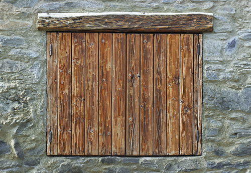 wooden shutters closed on a stone facade of a mountain chalet