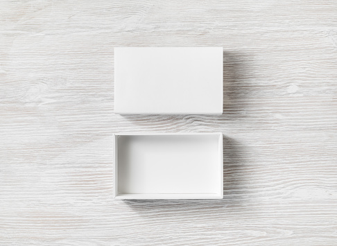 White cardboard box with cover on light wooden background. Flat lay.