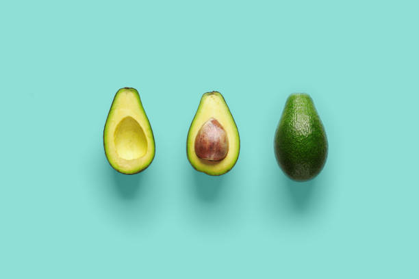 istock Whole avocado fruit and two halves in a row isolated on blue background 1150659705