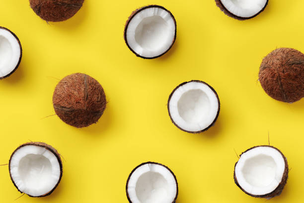 Pattern with ripe coconuts on yellow background. Pop art design, creative summer concept. Banner. Half of coconut in minimal flat lay style stock photo