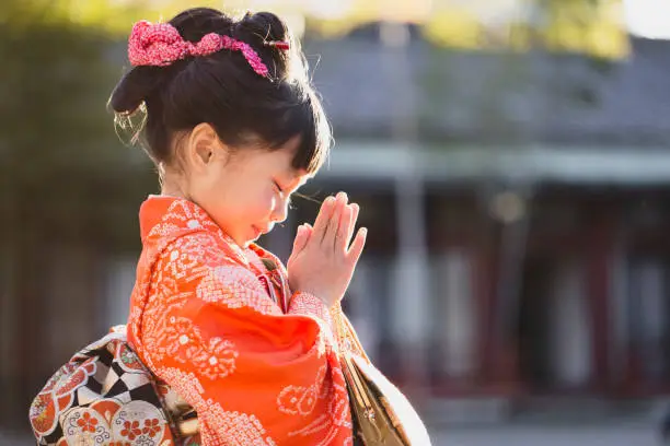 Japanese girl wearing Kimono praying at Shichi-go-san which is Japanese traditional life event celebrating children's health and growth when they are 7, 5 or 3 years old.