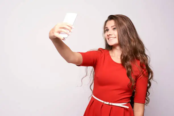Portrait girl. Selfie on phone. Red dress.
