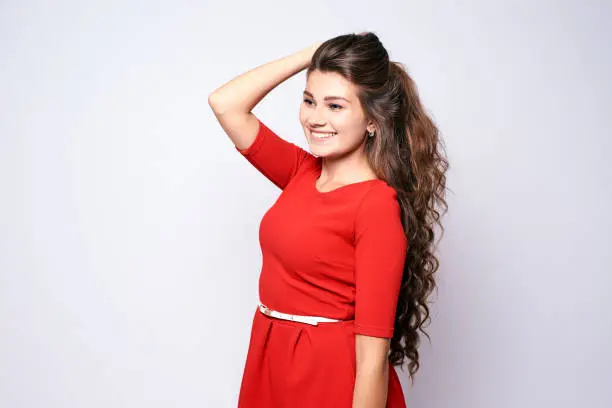 Portrait girl. Beautiful brunette. Red dress. White background.