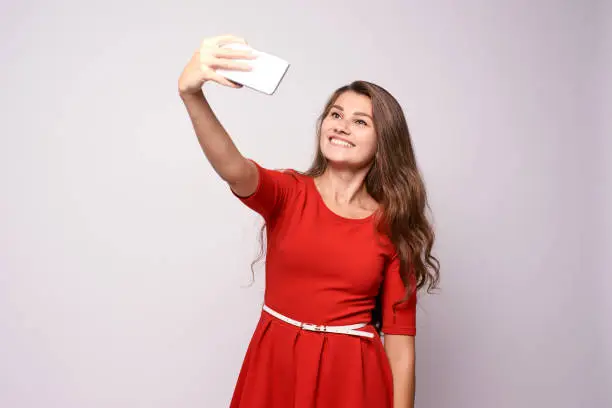 Portrait girl. Red dress. Selfie on phone.