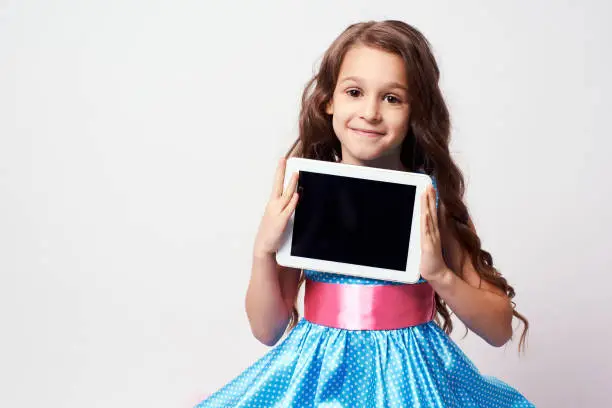 Beautiful little girl. Modern technologies. Lush blue dress.