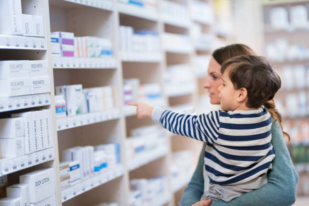 мать со своим малышом глядя на лекарства - pill bottle pharmacy medicine shelf стоковые фото и изображения