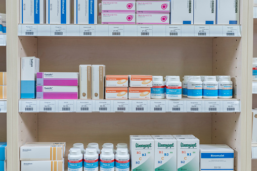 Pharmacy shelves stacked with medicine bottles and boxes.